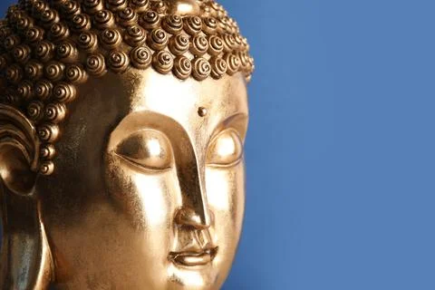 Beautiful golden Buddha sculpture on blue background, closeup. Space for text Stock Photos