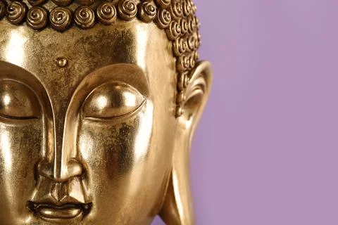 Beautiful golden Buddha sculpture on violet background, closeup. Space for te Stock Photos