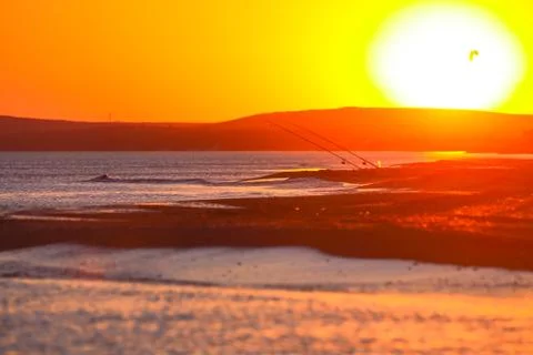 Beautiful golden sunset on the beach with fishermen and kitesurfers Stock Photos