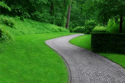 Beautiful green park with paved pathway. Landscape design Stock Photos