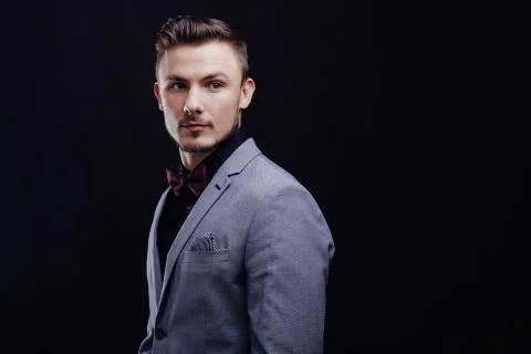 Beautiful guy in gray jacket looking forward on dark background Stock Photos