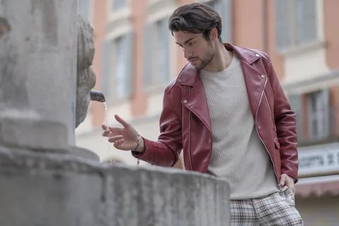 Beautiful guy with red leather jacket and backpack in the center of reggio em Stock Photos