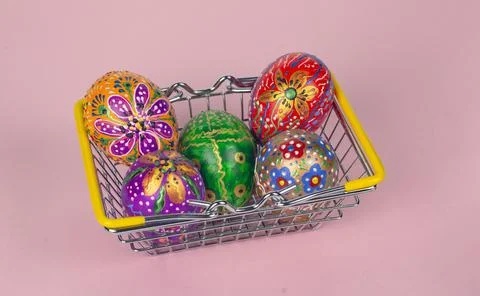 Beautiful hand painted Easter eggs in a basket from the supermarket on a pink Stock Photos