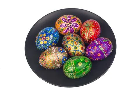 Beautiful hand-painted easter eggs on a large black plate. Isolated image 库存照片