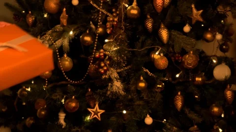 Beautiful hands give a gift on the background of the Christmas tree. Orange gift Stock Footage 120134109