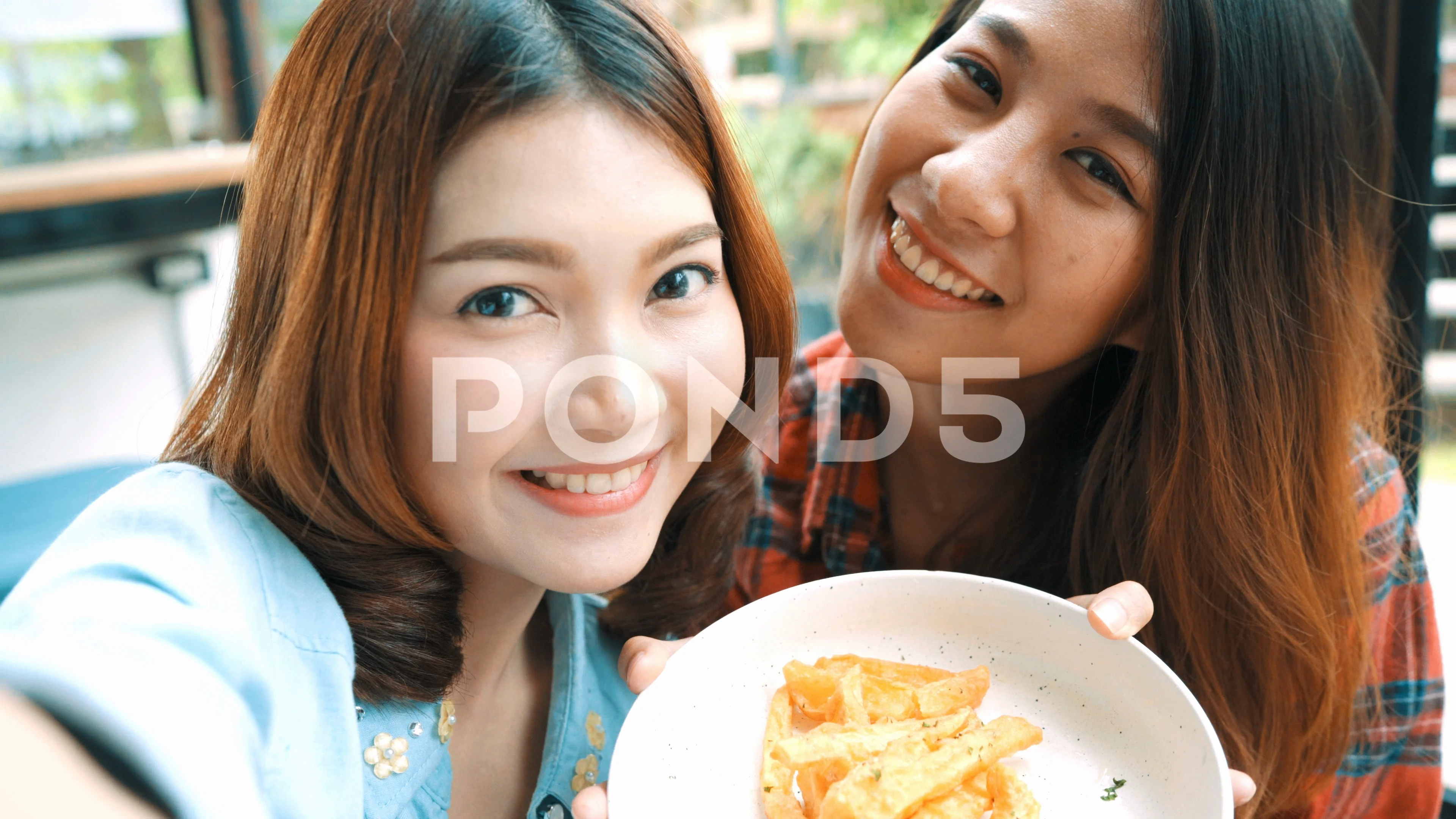 Beautiful happy Asian women lesbian lgbt couple sitting each side eating.