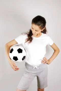 Beautiful happy girl in a sports T-shirt holds a soccer ball. Gray background Stock Photos
