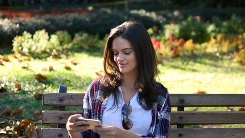 Beautiful happy model taking selfie in park sitting on the bench Stock Footage 101565710