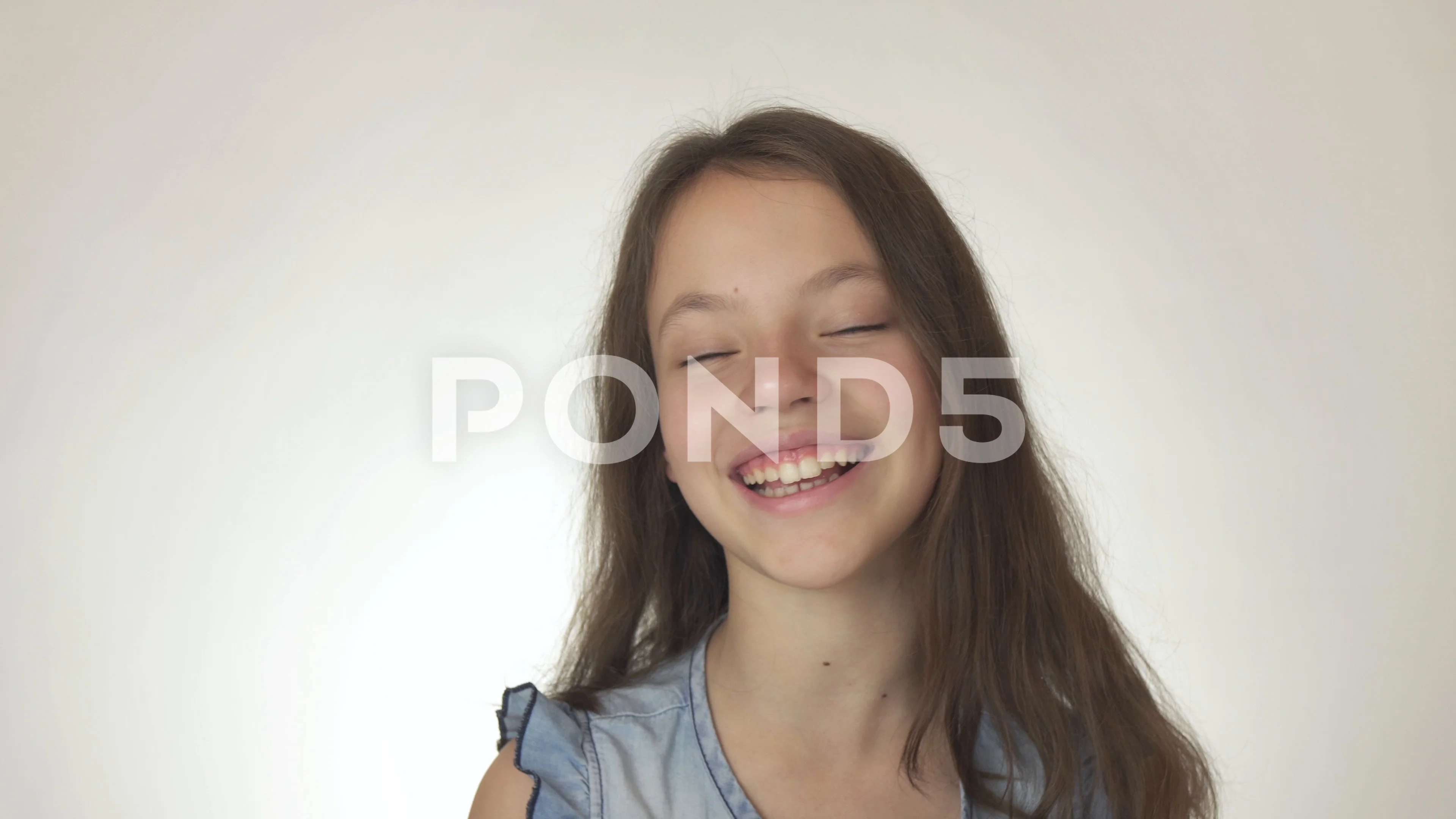 Portrait of caucasian teen girl, isolated on white background. Beautiful  young teenager smiling with wind in her hair. Happy cute child laughing.  Stock Photo