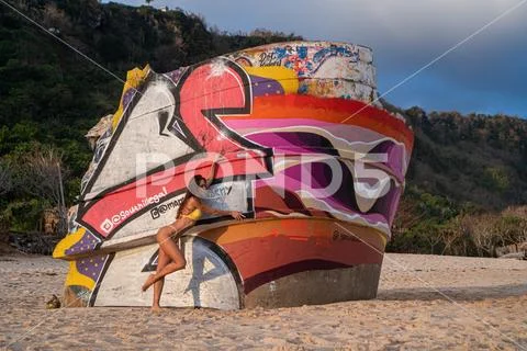 Beautiful happy woman in yellow bikini posing near the shipwreck at the beach Stock Photos