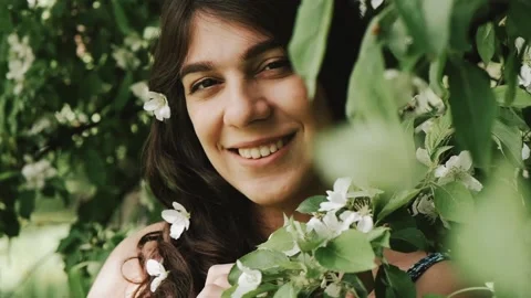 Beautiful happy young dark-haired woman enjoys blooming apple trees. Stock Footage 199241116