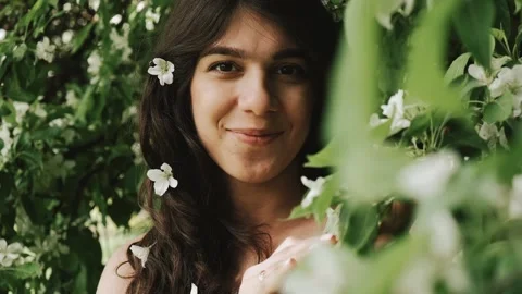 Beautiful happy young dark-haired woman enjoys blooming apple trees. Stock Footage 199241132