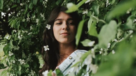 Beautiful happy young dark-haired woman enjoys blooming apple trees. Stock Footage 199241143