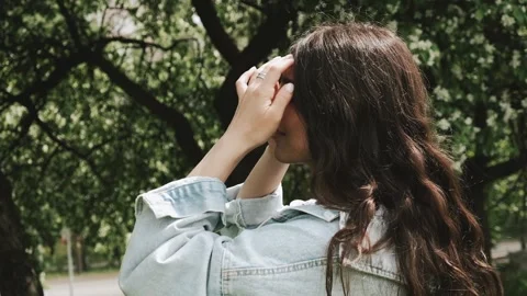 Beautiful happy young dark-haired woman strokes her hair on a summer day. Stock Footage 199241253