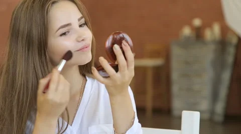 Beautiful happy young lady putting makeup in front of mirror Stock Footage
