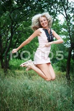 Beautiful happy young woman jumping high in air in the park Stock Photos