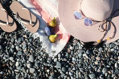 Beautiful hat with sunglasses and flip flops on pebbles, flat lay. Space fo.. Stock Photos