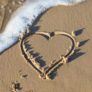 A beautiful heart shape painted into the sand of a baltic sea beach with some Stock Photos