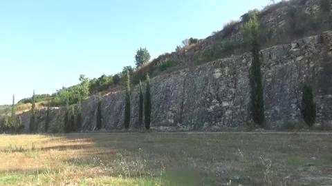 A beautiful high stone wall along which thuja trees grow Video stock 336456912