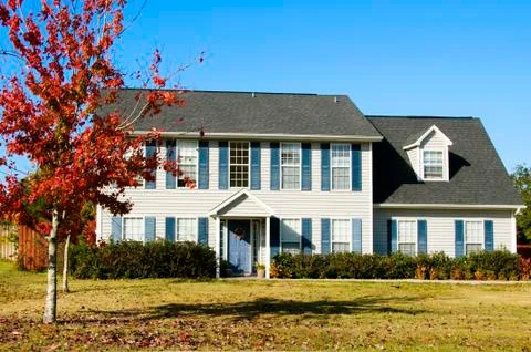Beautiful home with a fall red leaf maple tree and blue sky Stock Photos