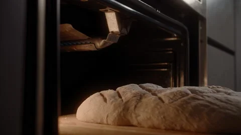 Beautiful homemade rustic bread with a pattern is placed in the oven Stock Footage 168816524