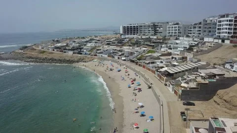 Beautiful horizontal aerial drone view of people on the beach sunbathing with um Video stock 195993445