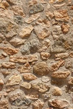 A beautiful horizontal texture of an old wall from gray and orange stones wit Stock Photos