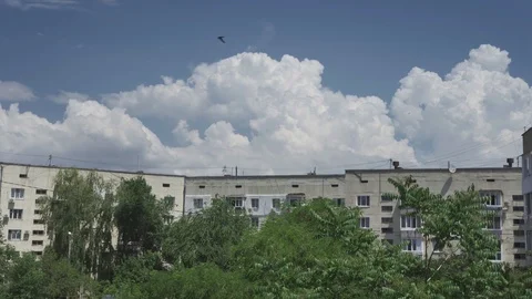 Beautiful huge clouds fly over high-rise buildings. Swallows fly around. Stock Footage 110797139