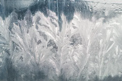 Beautiful ice pattern on a glass window in the backlight of the winter sun Stock Photos