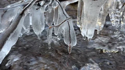 Beautiful icicle formations during the freezing of the stream in winter Stock Footage 296653549