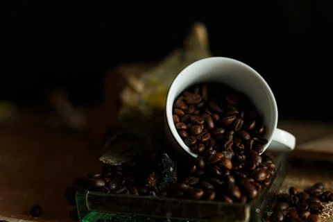 This beautiful image shows coffee beans spilling from a cup, perfect for coff Stock Photos