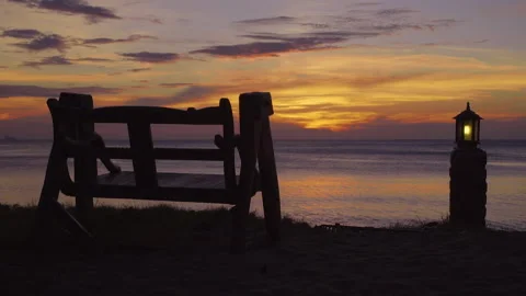Beautiful inviting bench facing tropical sun setting over ocean Stock Footage 143877175