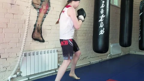 Beautiful Kickboxing woman training punching bag in fitness studio fierce Stock Footage