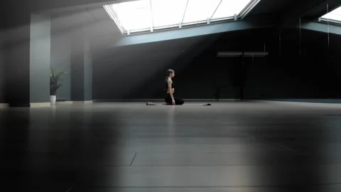 A beautiful lady does yoga exercises sitting under a huge window on the ceiling Stock Footage 170227724