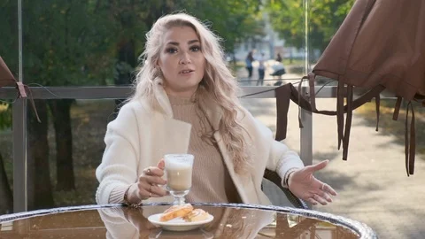 Beautiful lady is recording a video blog in an outdoor cafe. Stockbeeldmateriaal 117909341