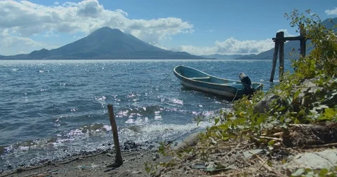 Beautiful Lake Atitlan view with distant volcano, deserted boat in water and  Stock-Footage 123117748