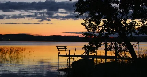 Beautiful lake view sunset on a summer evening, dock and tree in foreground. Stock Footage 112112976