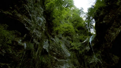 Beautiful landscape, a small waterfall flows down the green-covered rocks, a Video stock 131064417