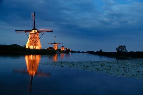 Beautiful landscape view with a row of Dutch windmills near the canal in the eve Stock Illustration