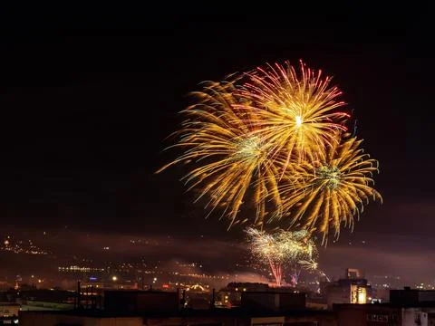 Beautiful large firework splashes high in the night sky over a city. Foto stock