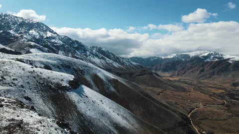 Beautiful large mountains, covered with clouds and snow. Aerial flight in Stock Footage 163239549