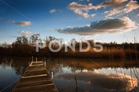 Beautiful late evening sunset landscape over jetty on lake Stock Photos