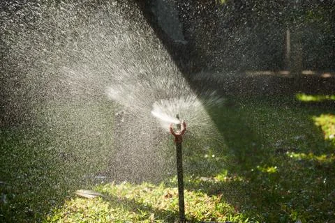 Beautiful light and spray from automatic sprinkler Stock Photos