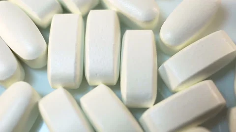 Beautiful light beige large long pills in a shiny shell move smoothly in the fra Stock Footage 144643346