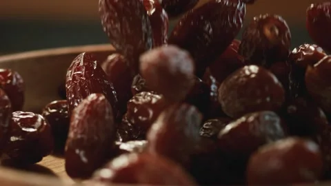 In a beautiful light, dried date fruit fall into the wooden plate. Stock Footage 140517394