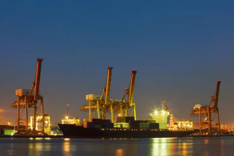 Beautiful lighting of freight container comercial ship with ship yard crane t Stock-Fotos