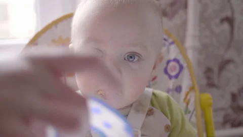 Beautiful little boy sitting at the table, eating a cookie and watching into the Stock Footage 103228310