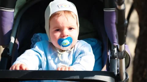 Beautiful little boy in a stroller with a pacifier in nature Stock Footage 65139596