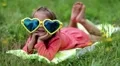 Beautiful little girl in big sunglasses lies on the grass HD Footage