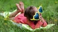 Beautiful little girl in big sunglasses lies on the grass HD Footage